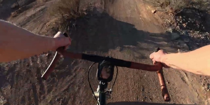 A view of handlebars on a dirt trail.