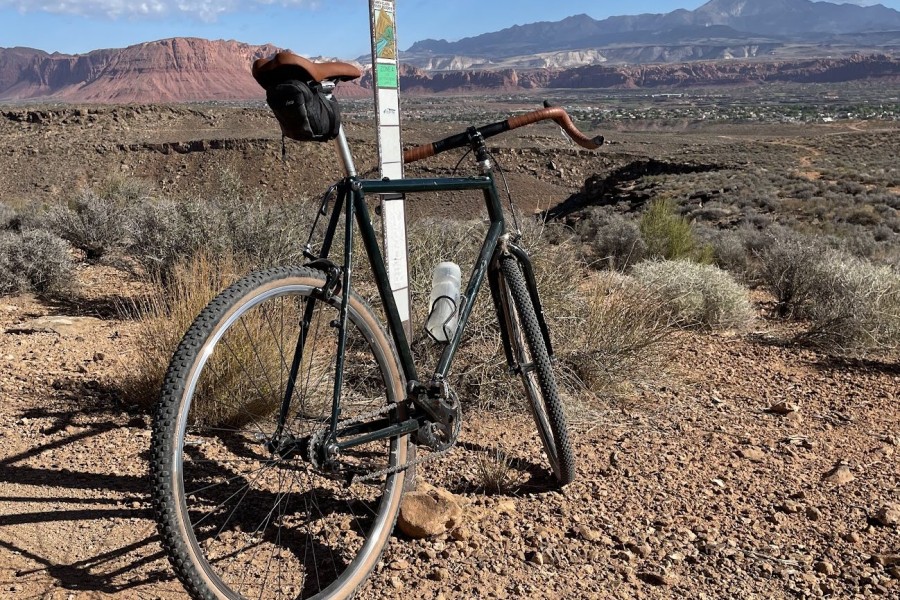 Dark green steel gravel bike with brown bar tape standing in the desert outside St. George, Utah