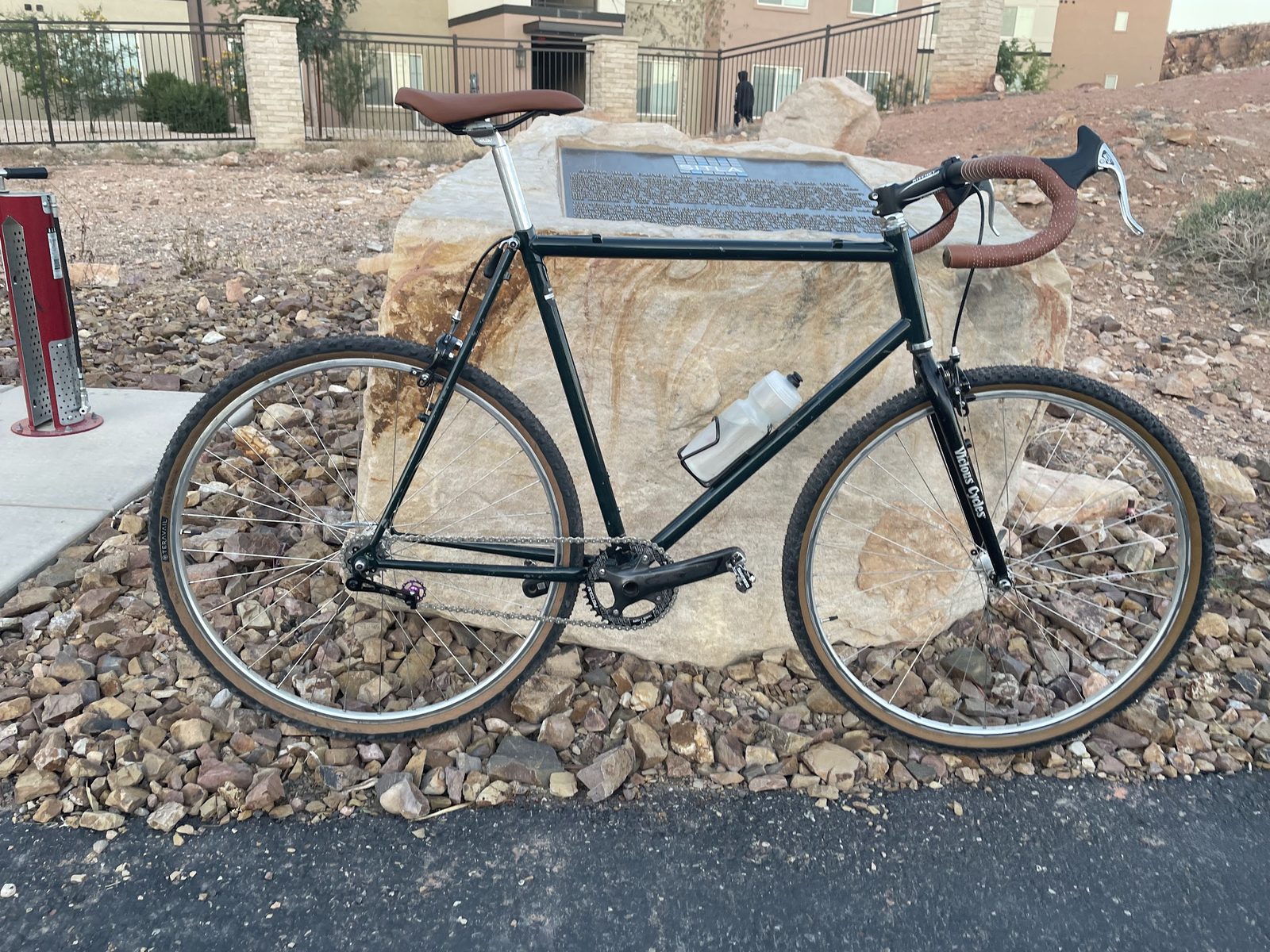 The singlespeed with a brown saddle and bar tape, leaning on a boulder