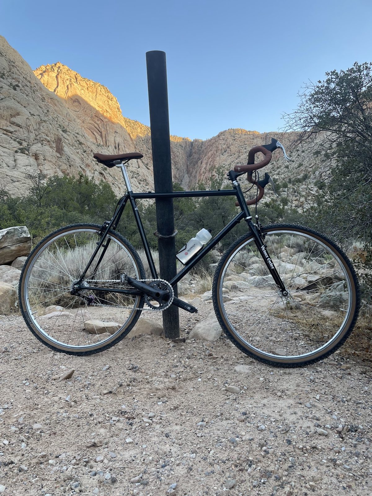 The bike leaning against a post in a red rock canyon at sunset