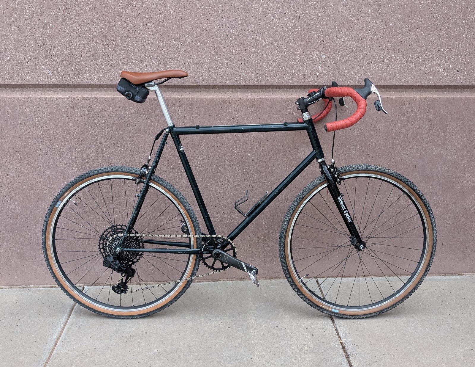 The finished 12-speed build with red bar tape against a pink wall