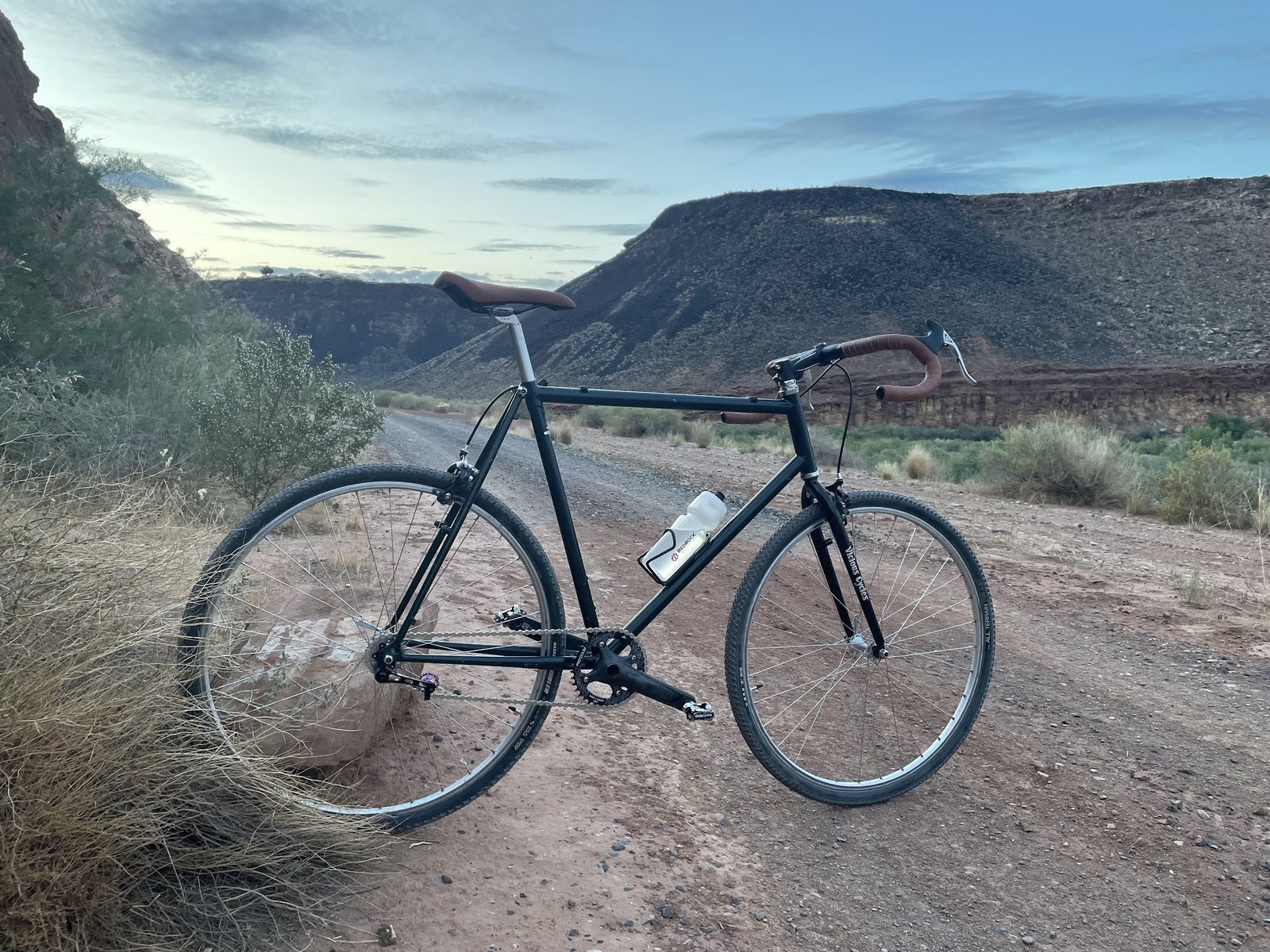 The singlespeed build on a dirt road with red cliffs behind it